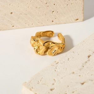 Irregular lava texture gold ring in titanium steel on minimalist travertine stone background