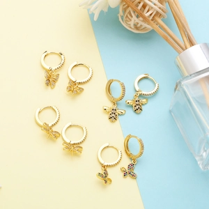 Macro shot of gold-plated insect hoop earrings with zircon-encrusted bees and butterflies