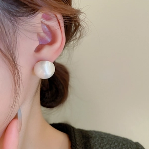 Close-up of minimalist brushed hemisphere stud earring worn on model's earlobe