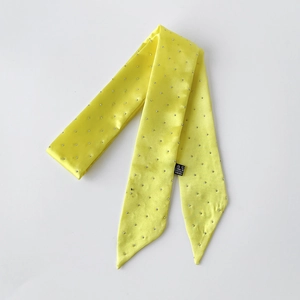 Detail eines gelben Satin-Schals mit silbernen Nieten und einer weichen, glatten Textur