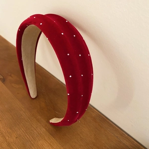 Macro detail of red velvet padded headband with sparkling white rhinestone embellishments
