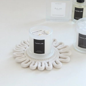 Macro detail of hand-woven white cotton cord coaster with minimalist floral petal edges