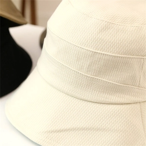 Macro shot of cream white bucket hat showing thick ribbed texture and premium stitching