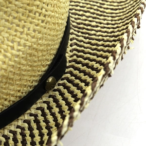 Detail of raffia straw hat with striped brim edge and black leather band with metal studs