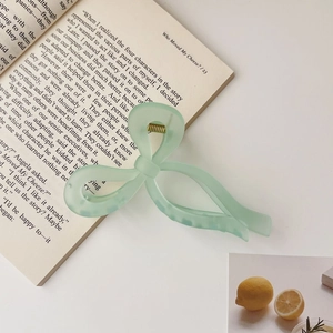Detail of light green jelly bow hair claw clip showing a strong gold metal spring