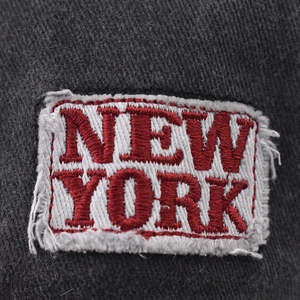 Détail macro de la broderie rouge New York sur une casquette de baseball grise délavée