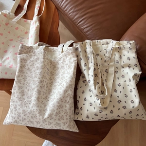 Detailed view of three floral cotton tote bags with vintage prints on a wooden surface