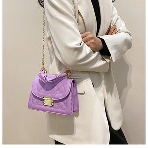 Detalle de bolso bandolera acolchado morado con cadena dorada y asa de mano en modelo