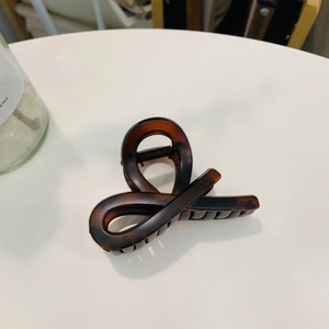 Detail view of tortoiseshell hair claw clip showing glossy resin pattern and metal spring