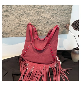 Detail of bohemian burgundy fringe bag with sun embossed pattern and metal rivets