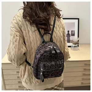Détail d'un mini sac à dos léopard avec texture pelucheuse et fermetures éclair noires