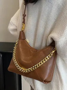 Brown quilted leather hobo bag with gold chain strap shown on a white sweater model