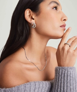 Close-up of minimalist silver ball bead ring and C-shape earrings on a model