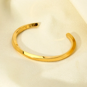 Minimalist 18K gold-plated twisted open cuff bracelet on elegant silk background