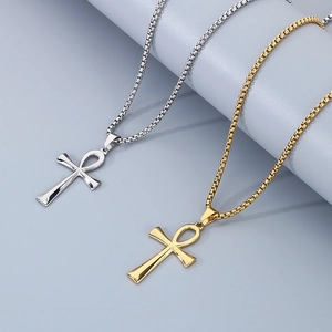 Detail of silver and gold Ankh cross pendant necklaces on a minimalist grey surface