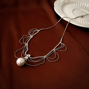 Detail of layered silver chain necklace with shimmering rhinestones and a large pearl