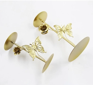 Close-up of golden iron candle holders featuring delicate metal butterfly and rose details