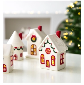 Close-up of white ceramic Christmas house ornament with festive red and green hand-painted details