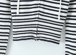 Detail aus schwarz-weiß gestreiftem Strickstoff mit Metallreißverschluss und Kordelzug