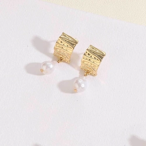 Detail of 14K gold plated earrings with irregular texture metal and a white pearl