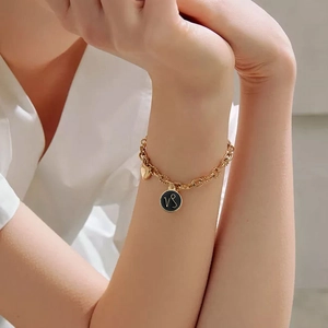 Gold chain bracelet featuring a circular Capricorn zodiac symbol charm on a female wrist