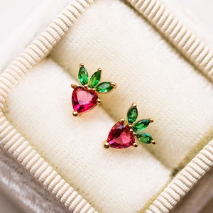 Macro shot of red heart-shaped zircon fruit stud earrings in a white velvet jewelry box