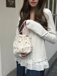 Close-up detail of a white quilted cartoon drawstring storage pouch held by a model