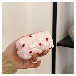 Close-up of a small quilted pink cotton pouch with red heart patterns and ribbon bow