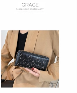 Detail einer schwarzen Lederclutch mit Metallnieten und goldenem Reißverschluss