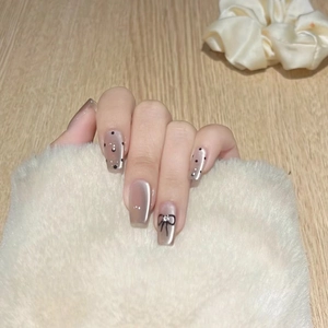 Macro view of French press-on nails with black polka dots and 3D bow jewelry accents