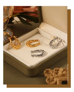 Detailed close-up of gold and silver twisted hoop earrings in a luxury velvet jewelry box