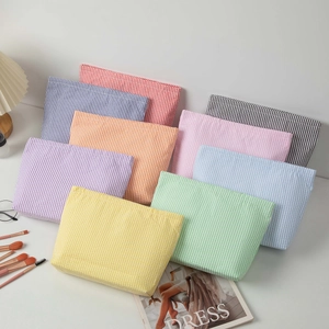 Detailed top view of various colorful striped seersucker cosmetic bags in a lifestyle setting