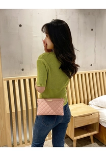 Pink quilted clutch bag with gold chain strap shown on a model in a lifestyle setting