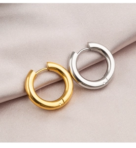 Close-up of polished gold and silver hoop earrings on elegant silk fabric