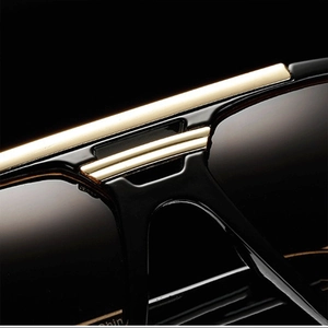 Macro detail of square frame sunglasses showing gold metal bridge and polished finish