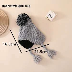 Close-up of grey knit baby winter hat with fur pompom and soft fleece lining detail