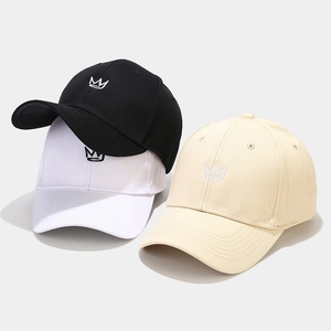 Detailed embroidery of a crown on cotton baseball caps in black, white, and beige colors