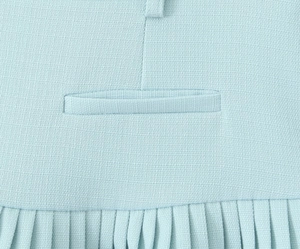 Close-up of light blue fabric texture showing welt pocket and pleated skirt hem details