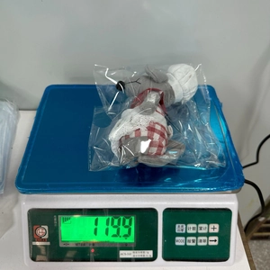 Detail showing plush Christmas mouse weight at 119.9g on a digital scale in packaging