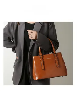 Minimalist caramel tote bag with glossy leather texture and stylish buckle details on model