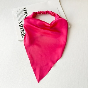 Close-up of rose red satin head scarf with elastic band on a magazine background