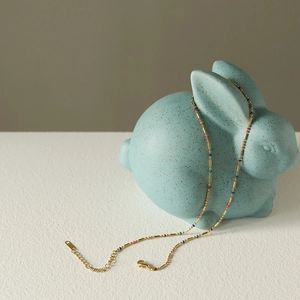 Colorful bohemian rainbow necklace in 18K gold plated steel on a blue rabbit stand