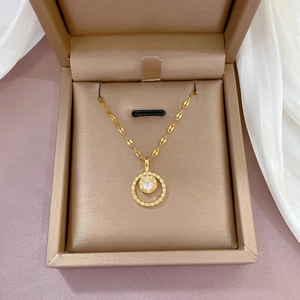 Golden round zircon pendant necklace on a lip chain displayed in a premium jewelry box