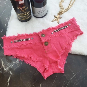 Detail von pinkfarbenen Denim-Shorts mit Strassbesatz und Fransen auf Marmor-Hintergrund