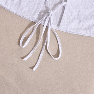 Dettaglio del crop top bianco con trama in tessuto a coste e design con lacci