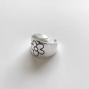 Detailed close-up of a silver flower ring with black agate daisy pattern detailing