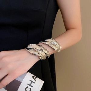 Detailed macro view of silver leaf texture wide open arm cuff bracelets on model