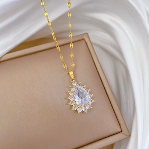 Macro shot of gold teardrop necklace pendant with sparkling halo zircons on silk