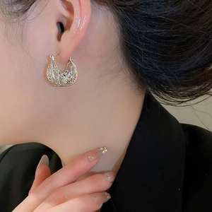 Detailed shot of silver hollow floral hoop earrings on model with retro French style