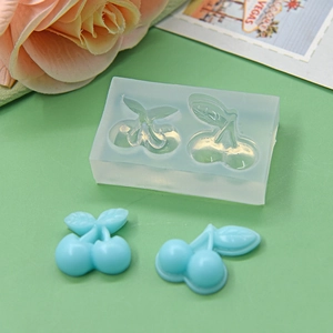 DIY cherry shaped silicone baking mold with light blue cherry resin crafts on green desk